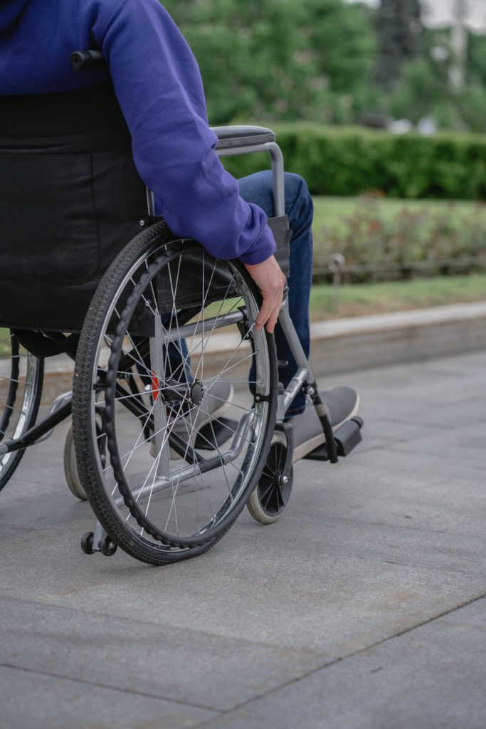 person in wheelchair traveling down the sidewalk